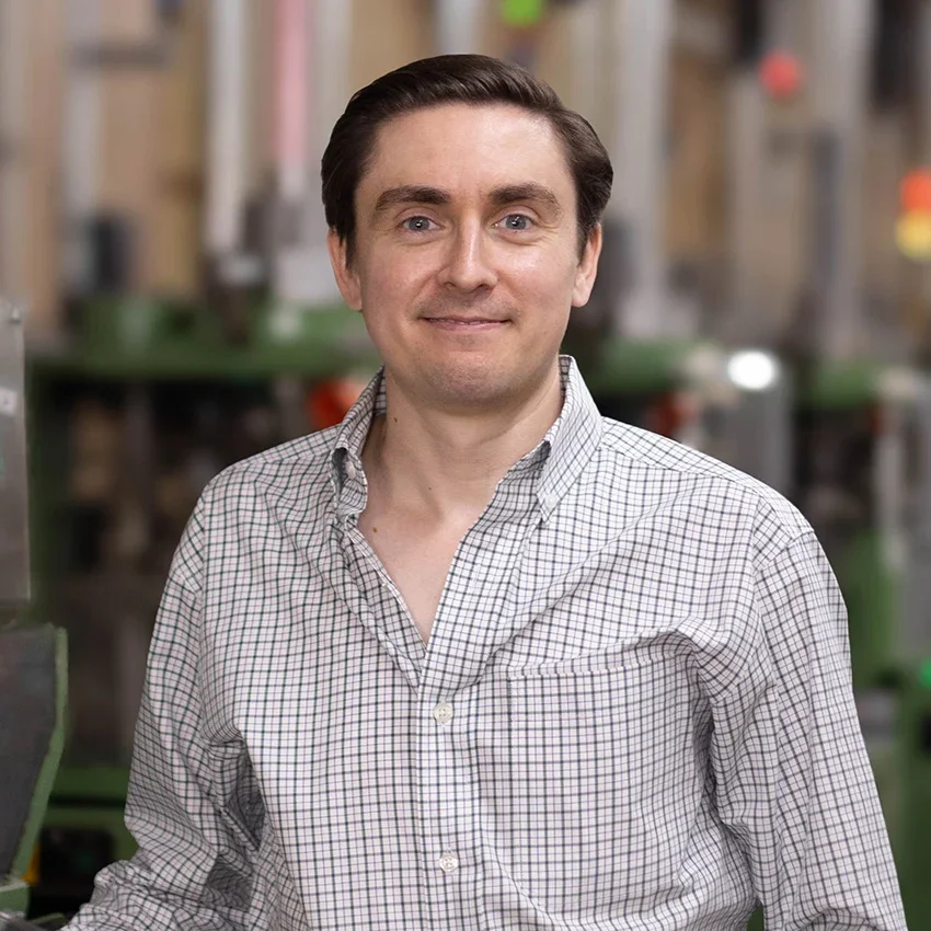Headshot of Nathan James, CEO of Boardroom Socks, in front of knitting machines.